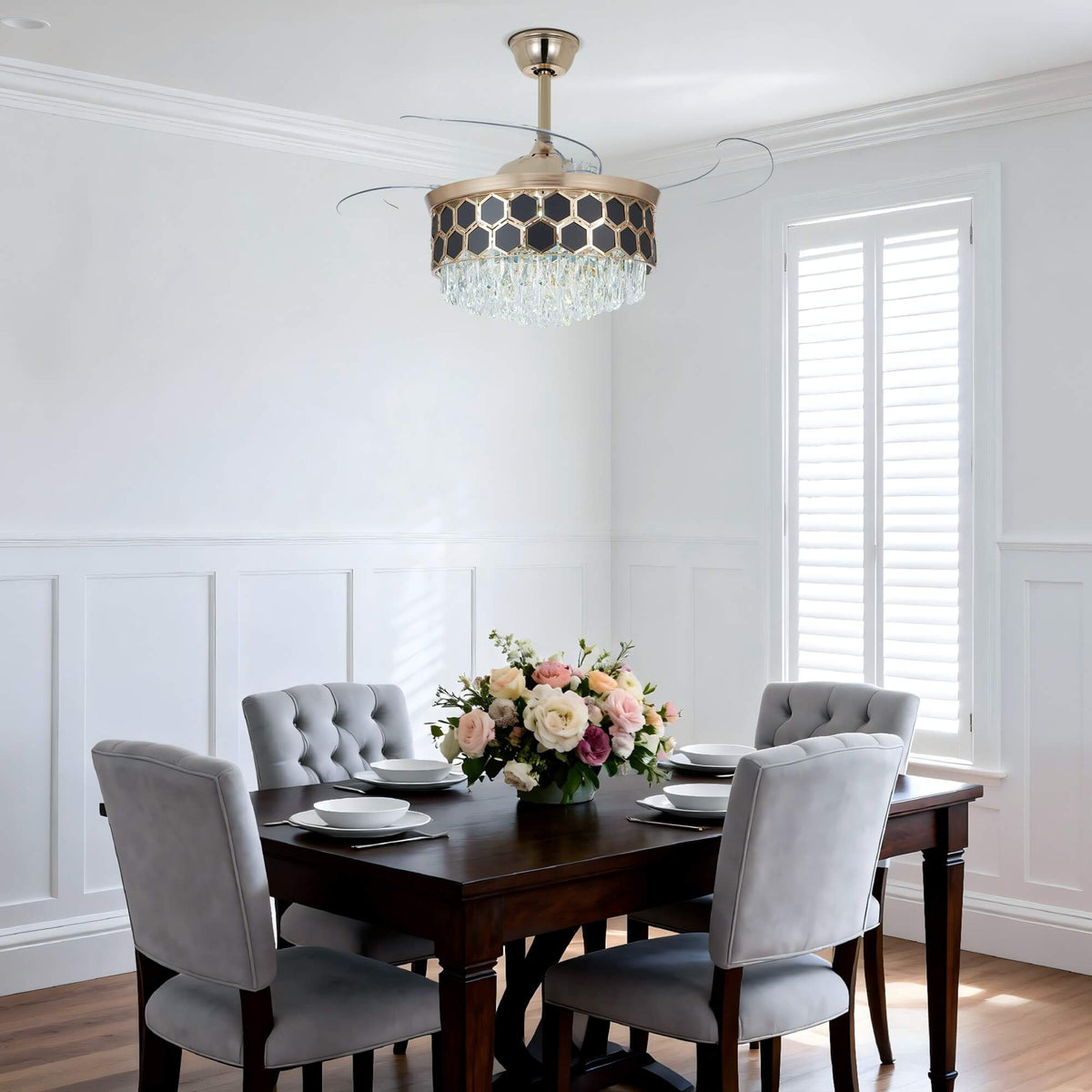 A view of the gold ceiling fan, with transparent blades above its crystal chandelier light.
